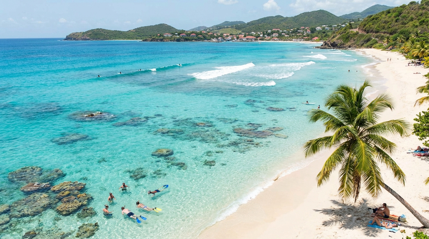 Vue aérienne de la plage du Souffleur à Port-Louis. Eaux turquoise, sable blanc, palmiers, baigneurs, surfeurs, collines verdoyantes.